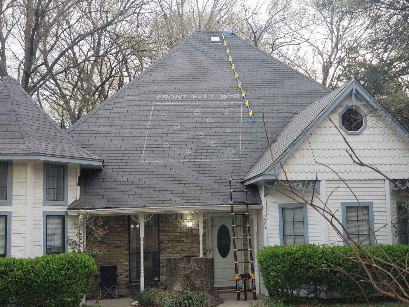 A chalk test square on the front slope of a steep roof during a HomFax forensic inspection — eleven circled hail strikes, no wind damage, ladder set at the eave